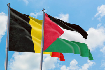 Palestine and Belgium flags waving in the wind against white cloudy blue sky together. Diplomacy concept, international relations.
