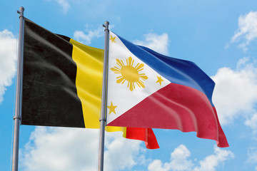 Philippines and Belgium flags waving in the wind against white cloudy blue sky together. Diplomacy concept, international relations.