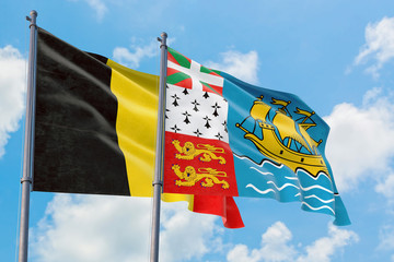 Saint Pierre And Miquelon and Belgium flags waving in the wind against white cloudy blue sky together. Diplomacy concept, international relations.