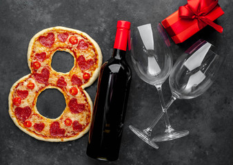 Dinner for two. Pizza in the form of 8, a bottle of wine and glasses, a gift for International Women's Day March 8 on a stone background. With copy space for your text. March 8 celebration concept.
