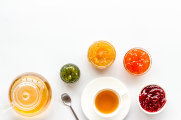 Fruit jam near tea on white kitchen desk copy space