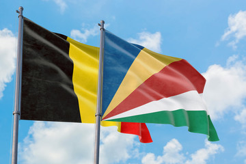Seychelles and Belgium flags waving in the wind against white cloudy blue sky together. Diplomacy concept, international relations.