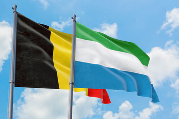 Sierra Leone and Belgium flags waving in the wind against white cloudy blue sky together. Diplomacy concept, international relations.