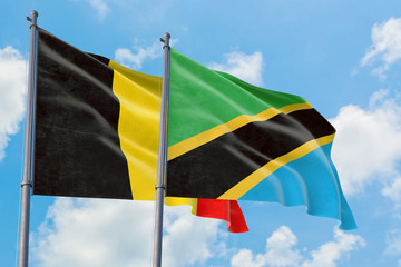 Tanzania and Belgium flags waving in the wind against white cloudy blue sky together. Diplomacy concept, international relations.