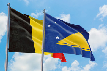 Tokelau and Belgium flags waving in the wind against white cloudy blue sky together. Diplomacy concept, international relations.