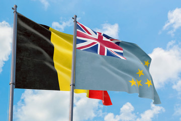 Tuvalu and Belgium flags waving in the wind against white cloudy blue sky together. Diplomacy concept, international relations.