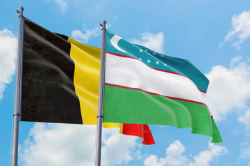 Uzbekistan and Belgium flags waving in the wind against white cloudy blue sky together. Diplomacy concept, international relations.