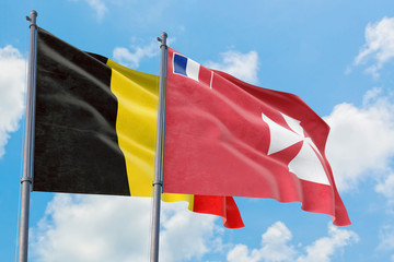 Wallis And Futuna and Belgium flags waving in the wind against white cloudy blue sky together. Diplomacy concept, international relations.