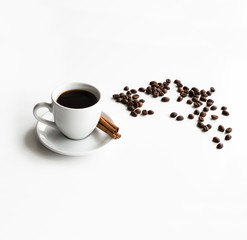 White cup of coffee with a saucer with cinnamon sticks on a white table scattered coffee grains with place for text top and bottom top view