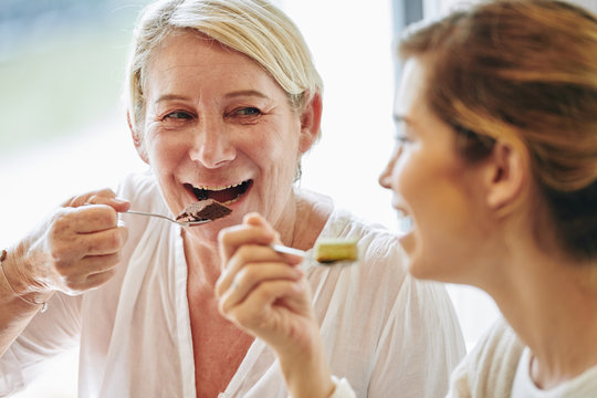 Happy Mature Woman Eating Delicious Chocolate Dessert And Listening To Her Daughter