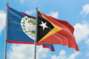 East Timor and Belize flags waving in the wind against white cloudy blue sky together. Diplomacy concept, international relations.