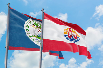 French Polynesia and Belize flags waving in the wind against white cloudy blue sky together. Diplomacy concept, international relations.