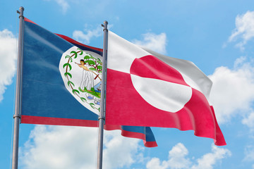 Greenland and Belize flags waving in the wind against white cloudy blue sky together. Diplomacy concept, international relations.