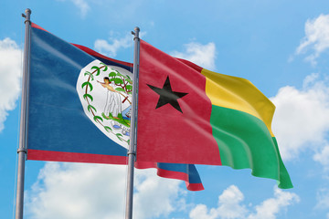 Guinea Bissau and Belize flags waving in the wind against white cloudy blue sky together. Diplomacy concept, international relations.