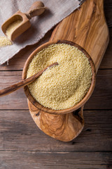 Couscous grain in wooden bowl. Top view