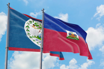 Haiti and Belize flags waving in the wind against white cloudy blue sky together. Diplomacy concept, international relations.