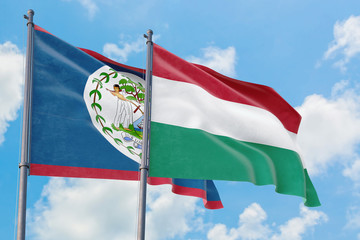 Hungary and Belize flags waving in the wind against white cloudy blue sky together. Diplomacy concept, international relations.