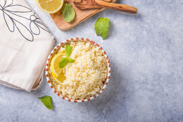 Couscous with mint and lemon in plate on dark rustic table from above. Copy space for text. Flat lay.