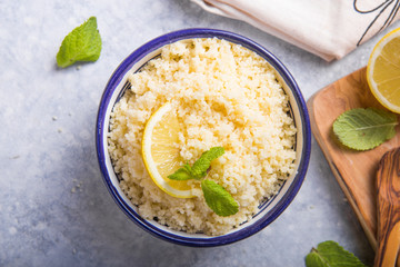 Couscous with mint and lemon in plate on dark rustic table from above. Copy space for text. Flat lay.