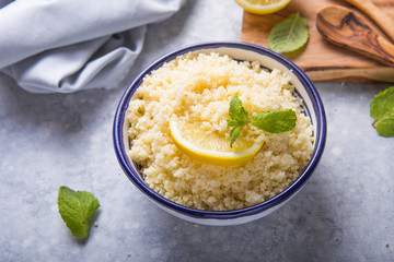 Couscous with mint and lemon in plate on dark rustic table from above. Copy space for text. Flat lay.