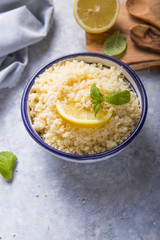 Couscous with mint and lemon in plate on dark rustic table from above. Copy space for text. Flat lay.