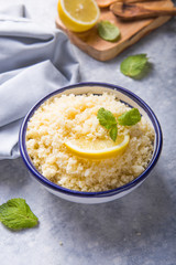 Couscous with mint and lemon in plate on dark rustic table from above. Copy space for text. Flat lay.