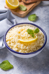 Couscous with mint and lemon in plate on dark rustic table from above. Copy space for text. Flat lay.