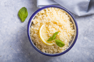 Couscous with mint and lemon in plate on dark rustic table from above. Copy space for text. Flat lay.