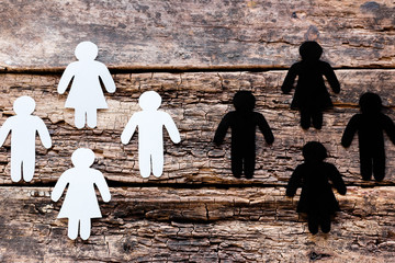 group of white and black silhouettes against each other on a wooden background. stop racism concept