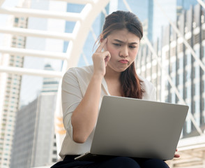 Businesswoman uses a laptop to think about after receiving email news in her notebook in the middle of the outside.
