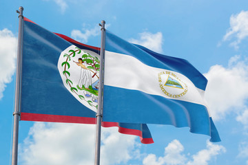 Nicaragua and Belize flags waving in the wind against white cloudy blue sky together. Diplomacy concept, international relations.