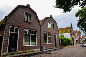 Fototapeta na wymiar Edam, the Netherlands, August 2019. The architecture of the Edam lodges is a characteristic example of the Netherlands. Red brick facade and red windows. Very fascinating.