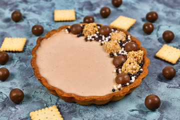 Fototapeta premium Sweet tart with cheesecake milk chocolate cream filling topped with pralines and chocolate sprinkles