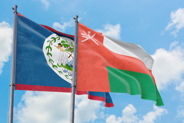 Oman and Belize flags waving in the wind against white cloudy blue sky together. Diplomacy concept, international relations.