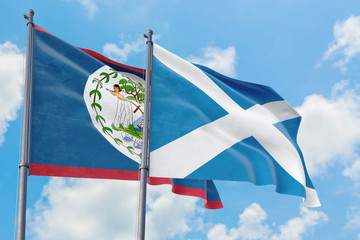 Scotland and Belize flags waving in the wind against white cloudy blue sky together. Diplomacy concept, international relations.