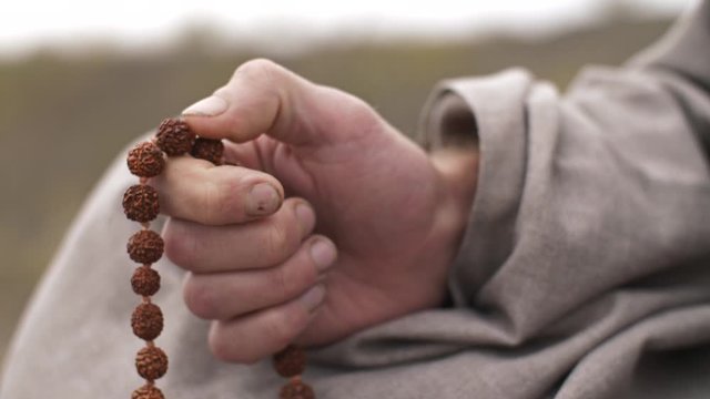 Man meditating with beads on nature