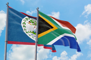 South Africa and Belize flags waving in the wind against white cloudy blue sky together. Diplomacy concept, international relations.