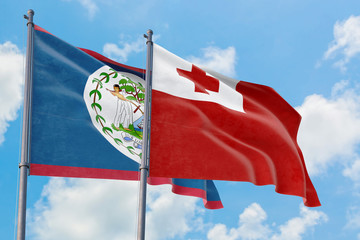 Tonga and Belize flags waving in the wind against white cloudy blue sky together. Diplomacy concept, international relations.