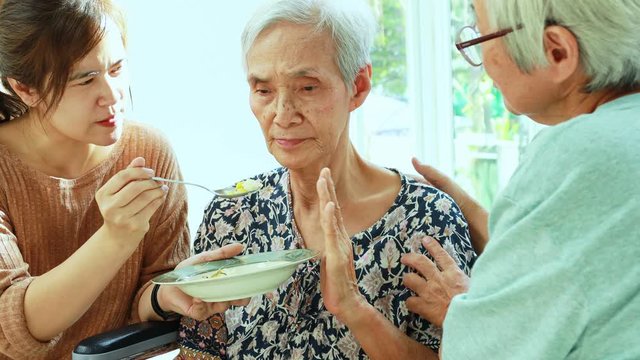 Unhappy asian senior woman rejecting,gesture hand &ldquo;NO&rdquo; elderly patient bored with food or boredom,old people getting sick and tired of food in wheelchair at home,loss of appetite,anorexia concept