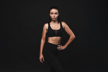 Image of young female model in sportswear standing on black background with copyspace