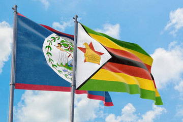 Zimbabwe and Belize flags waving in the wind against white cloudy blue sky together. Diplomacy concept, international relations.