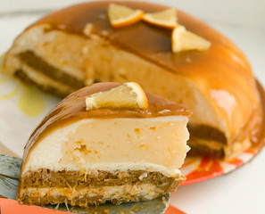 cut orange caramel mousse cake with cream cheese mascapone and chocolate glaze with nuts close up photo