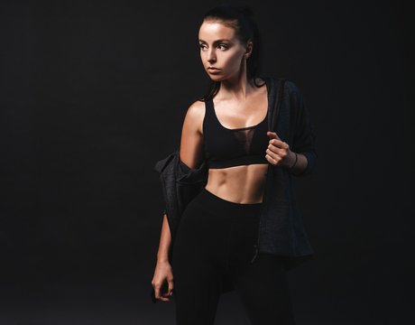 Image of young female model in sportswear standing on black background with copyspace