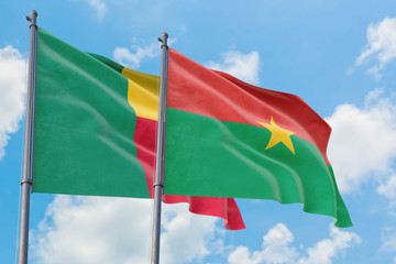 Burkina Faso and Benin flags waving in the wind against white cloudy blue sky together. Diplomacy concept, international relations.