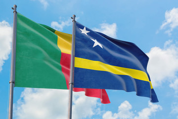 Curacao and Benin flags waving in the wind against white cloudy blue sky together. Diplomacy concept, international relations.