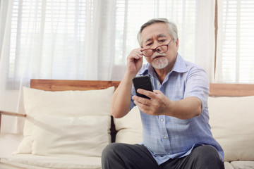Older men move glasses down to look at the phone in the hand due to Hyperopia problems, which makes vision difficult.Health problems of the elderly.