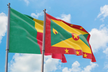 Grenada and Benin flags waving in the wind against white cloudy blue sky together. Diplomacy concept, international relations.