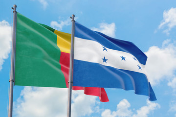 Honduras and Benin flags waving in the wind against white cloudy blue sky together. Diplomacy concept, international relations.