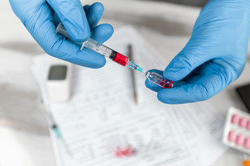 Doctor in rubber gloves is injecting vaccine into a syringe. Hands closeup gloved in medical protects the filled syringe with medication. Concept Coronavirus nCov 2019