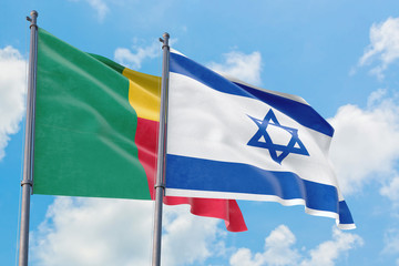 Israel and Benin flags waving in the wind against white cloudy blue sky together. Diplomacy concept, international relations.